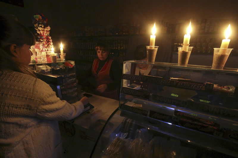 © Reuters. File photo of customer visiting grocery lit with candles due to power cut in Crimean city of Simferopol