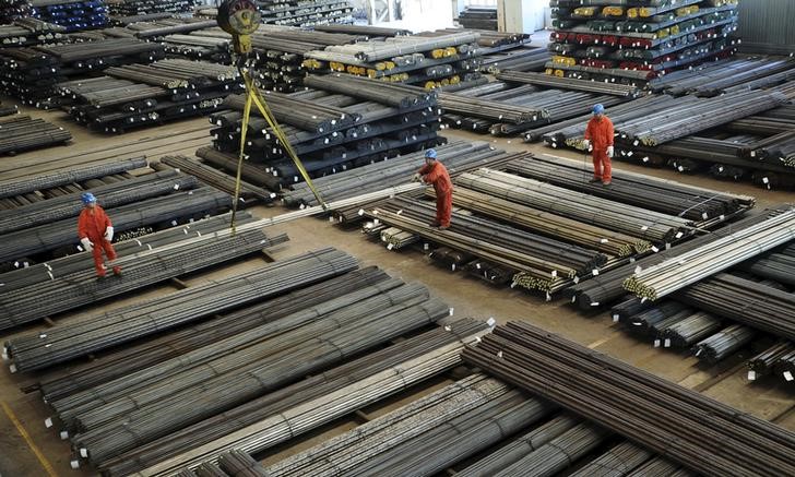 © Reuters. Workers direct a crane lifting newly-made steel bars at a factory in Dalian