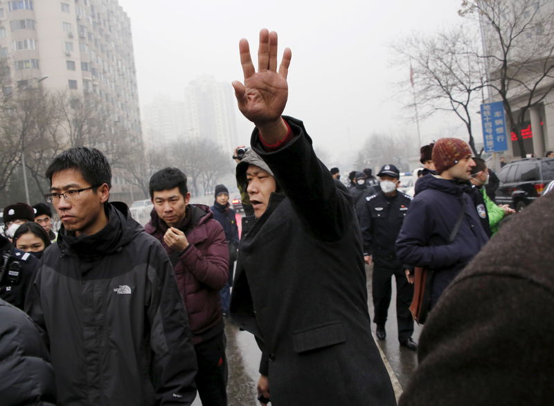 © Reuters. Plainclothes police officer gestures as he keeps China's rights lawyer Pu Zhiqiang's supporters and journalists away from the entrance of a court where Pu's trial is being held, in Beijing