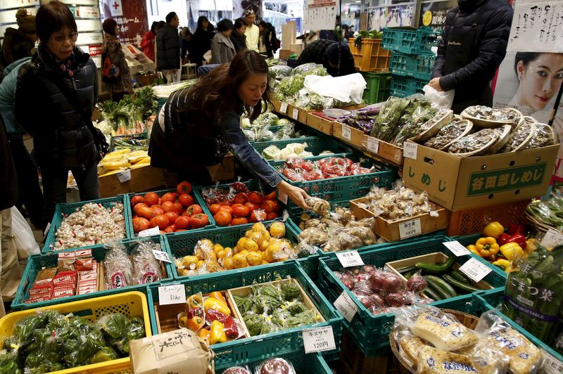 © Reuters. A shopper looks at packs of vegetables at a market at a shopping district in Tokyo