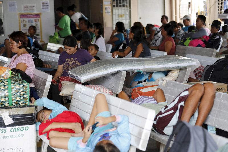 © Reuters. Pessoas aguardando no porto de Hagnaya após serem retiradas por conta de tufão nas Filipinas