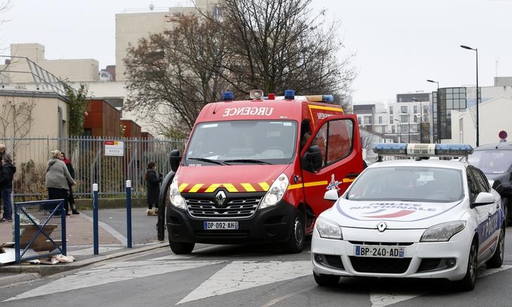 © Reuters. Carros da polícia e corpo de bombeiros vistos em frente escola onde homem foi atacado, em Aubervilliers