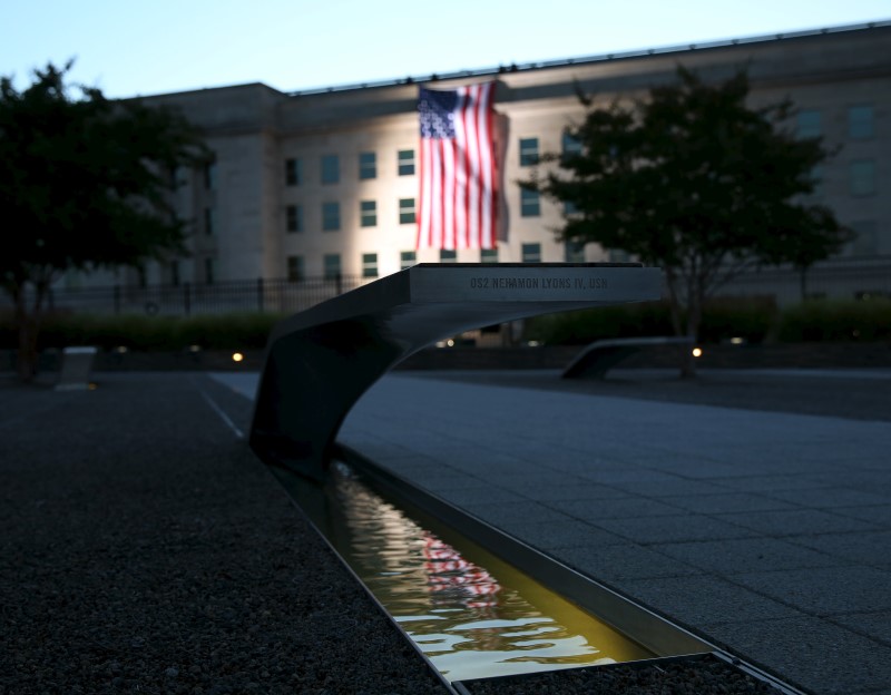 © Reuters. A United States flag is reflected at 9/11 Memorial after being at sunrise at the Pentagon on fourteenth anniversary of 9/11 attacks
