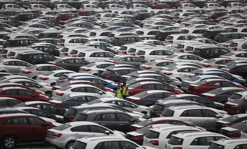 © Reuters. Workers walk between cars made by Hyundai and Kia at the company's shipping yard in Pyeongtaek