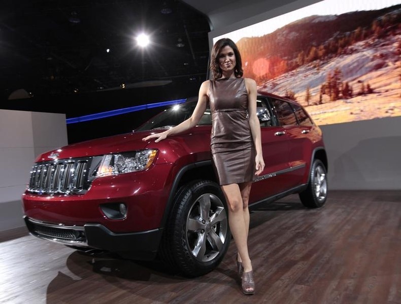 © Reuters. A model poses next to a Jeep Grand Cherokee on the final press preview day for the North American International Auto Show in Detroit