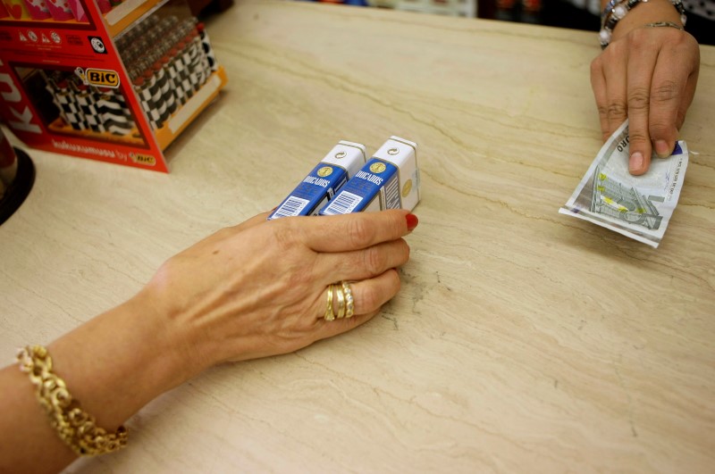 © Reuters. A woman buys a packet of cigarettes in Madrid