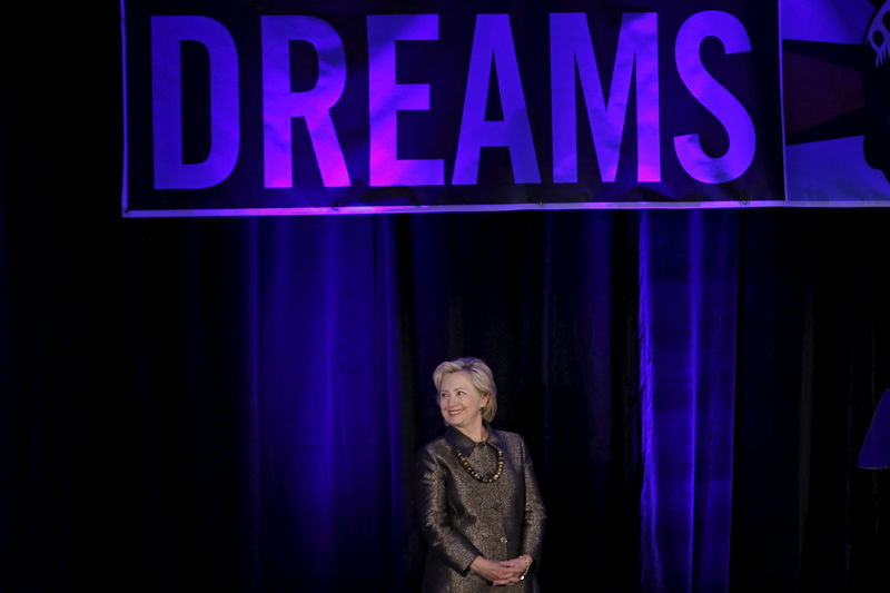 © Reuters. Democratic U.S. presidential candidate Hillary Clinton stands beneath a banner as she is introduced before addressing the 2015 National Immigrant Integration Conference in New York