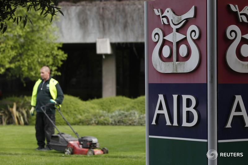 © Reuters. A gardener mows the grass outside the headquarters of AIB on the day the bank announced it's results, in Dublin