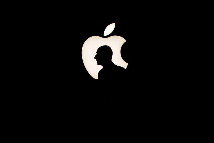 © Reuters. A man walks past a backlit Apple logo during an Apple media event in San Francisco