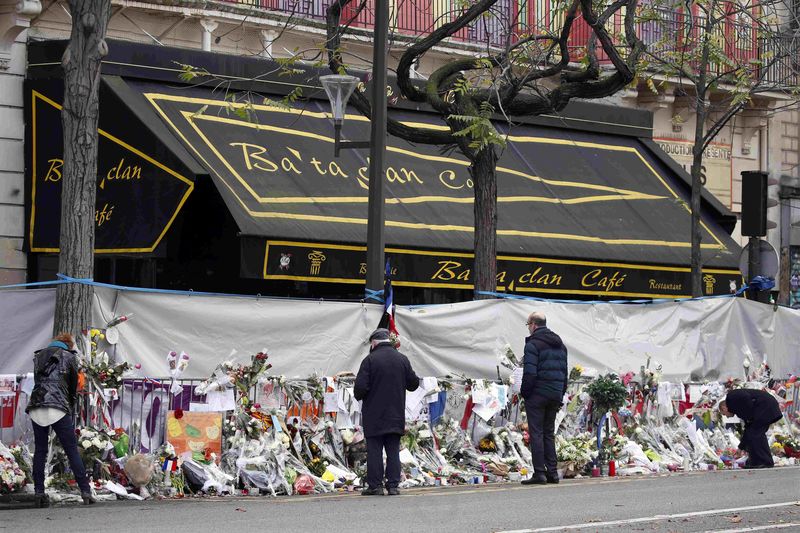 © Reuters. People mourn in front of the screened-off facade of the Bataclan Cafe adjoining the concert hall, one of the sites of the deadly attacks in Paris