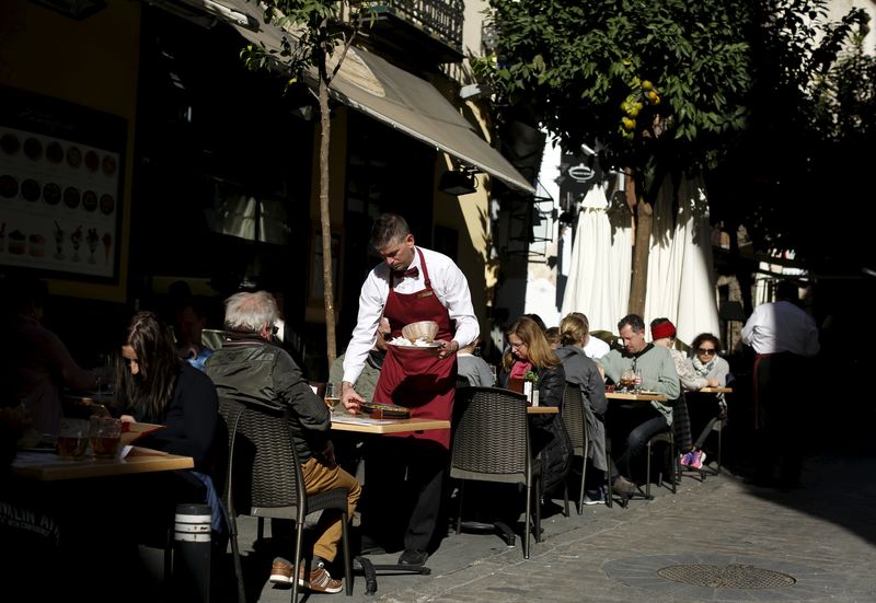 © Reuters. A waiter serves customers at a restaurant in the Andalusian capital of Seville