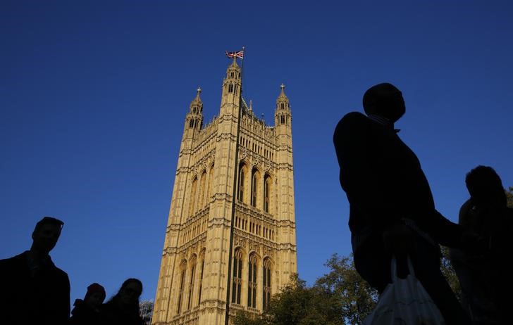 © Reuters. People are silhouetted against sky as they walk past the Houses of Parliament in central London