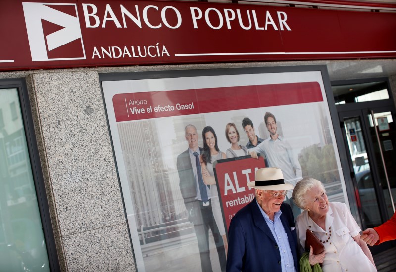 © Reuters. Couple smiles next to a Banco Popular branch office in the Andalusian capital of Seville