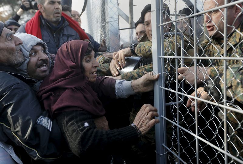 © Reuters. Syrian refugees struggle to enter Macedonia through a narrow border crossing as Macedonian policemen try to shut a metal gate near to the Greek village of Idomeni