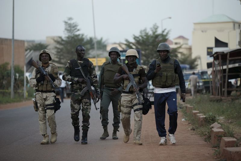 © Reuters. Malian soldiers walk in front of the Radisson hotel in Bamako