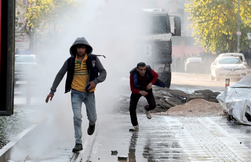 © Reuters. Riot police use a water cannon to disperse demonstrators during a protest against the curfew in Sur district