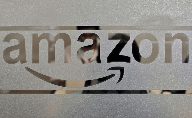 © Reuters. File photo of employees of Amazon India are seen behind a glass bearing the company's logo inside its office in Bengaluru