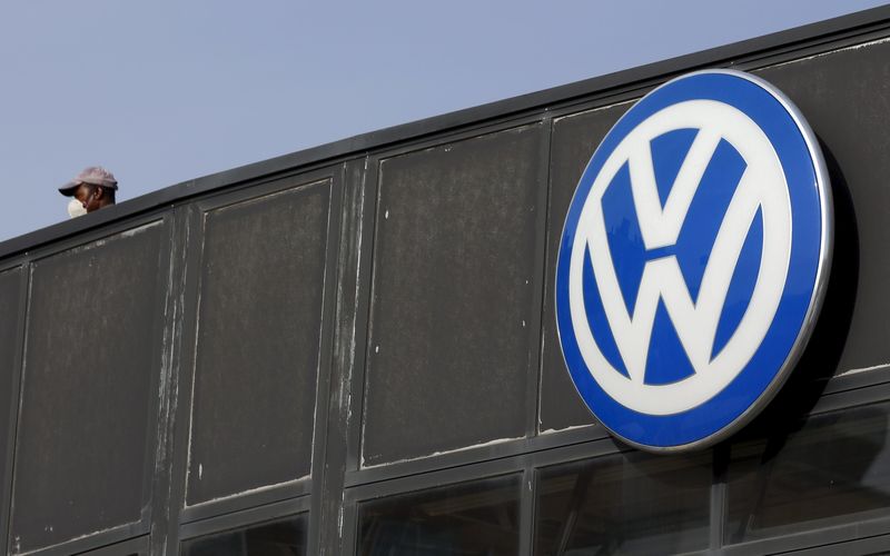 © Reuters. A worker wearing a protective mask stands next to a Volkswagen logo at a dealership in Madrid