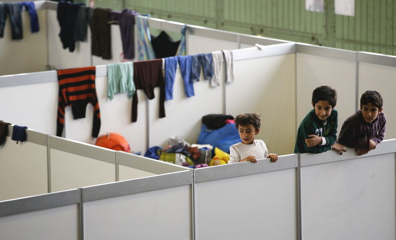 © Reuters. Children watch as they stand on beds in a shelter for migrants inside a hangar of the former Tempelhof airport in Berlin