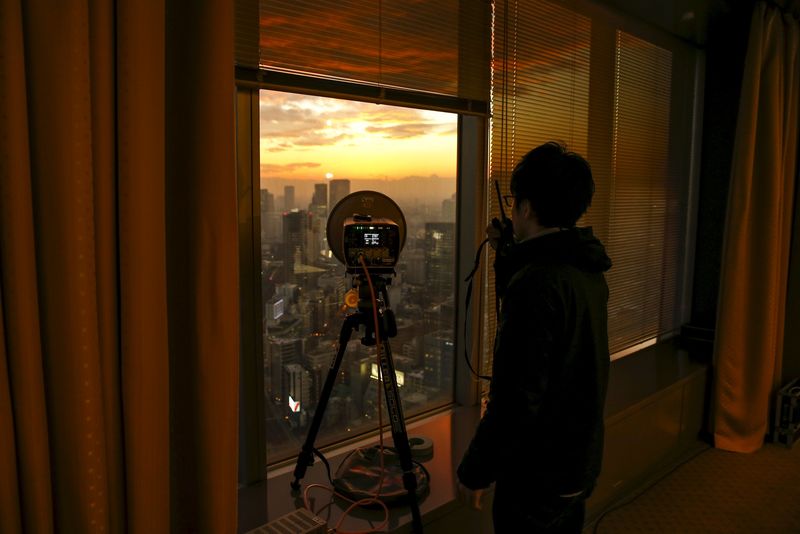 © Reuters. A TV technician talks with his newsroom about the signal strength a device is transmitting from the news conference room on 39th floor of the Toshiba head office as the sun sets over Tokyo