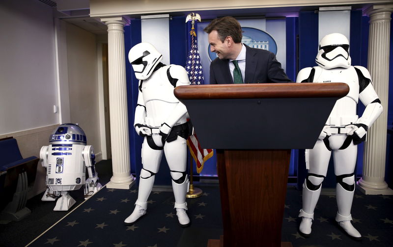 © Reuters. White House press secretary Earnest and Star Wars Stormtroopers wait for Star Wars Robot R2-D2 to enter the briefing room after U.S. President Obama finished his end of the year news conference at the White House in Washington