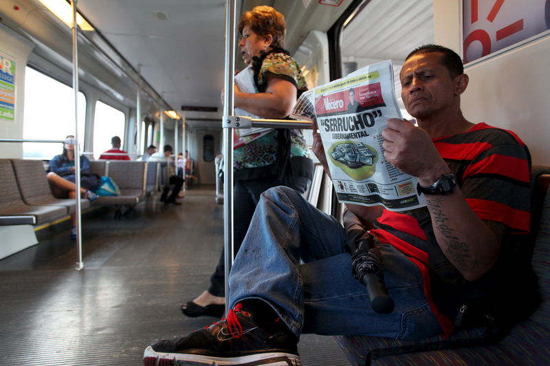 © Reuters. Harold Lopez reads a newspaper while riding on the metro train in San Juan