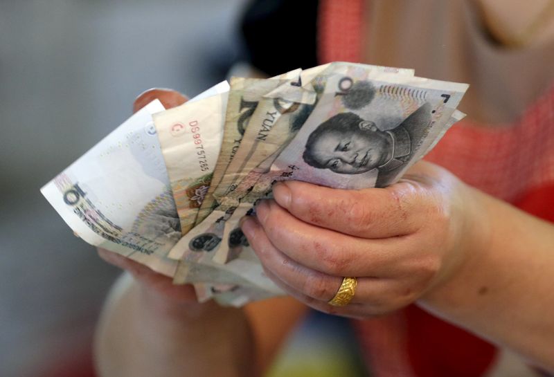 © Reuters. File photo of a vendor holding Chinese yuan notes at a market in Beijing