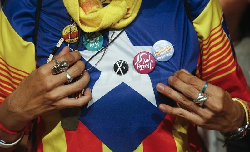 © Reuters. Junts Pel Si (Together For Yes) supporter displays pins after polls closed in a regional parliamentary election in Barcelona