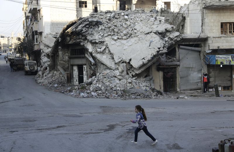 © Reuters. Menina em frente casas danificadas na província de Idlib, Síria