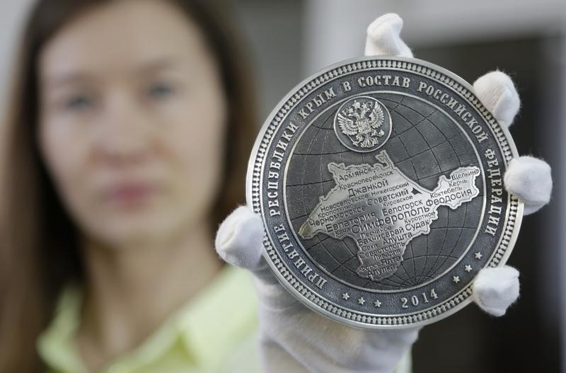 © Reuters. Employee of "Oruzheinik" factory shows back of commemorative coin from series "The Gatherer of Russian Lands", which was minted to mark recent accession of Crimea into Russian Federation, in Zlatoust in the Chelyabinsk region