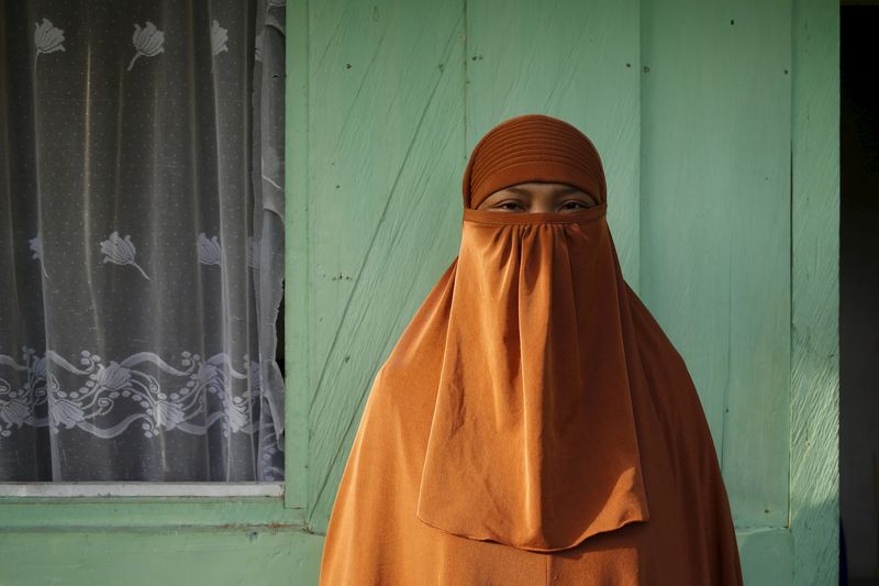 © Reuters. Suwarni, wife of Indonesian militant leader Santoso, poses for a picture in front of her house in Poso, Indonesia's Central Sulawesi province