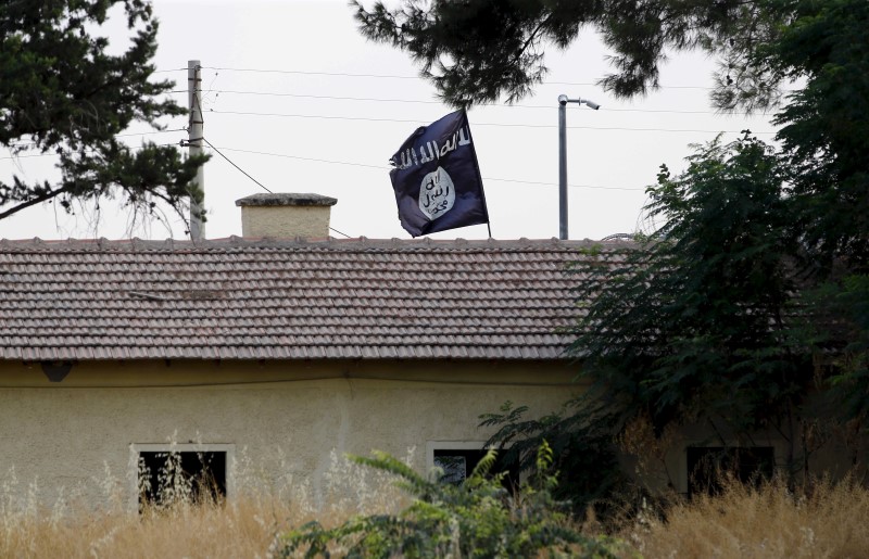 © Reuters. An Islamic State flag flies over the customs office of Syria's Jarablus border gate as it is pictured from the Turkish town of Karkamis