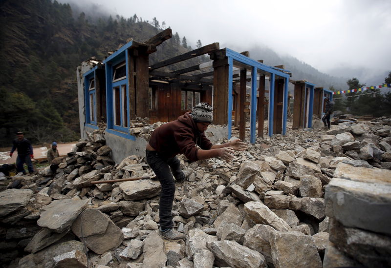 © Reuters. A man clears debris to rebuild a damaged lodge after the earthquake earlier this year in Solukhumbu district, also known as the Everest region