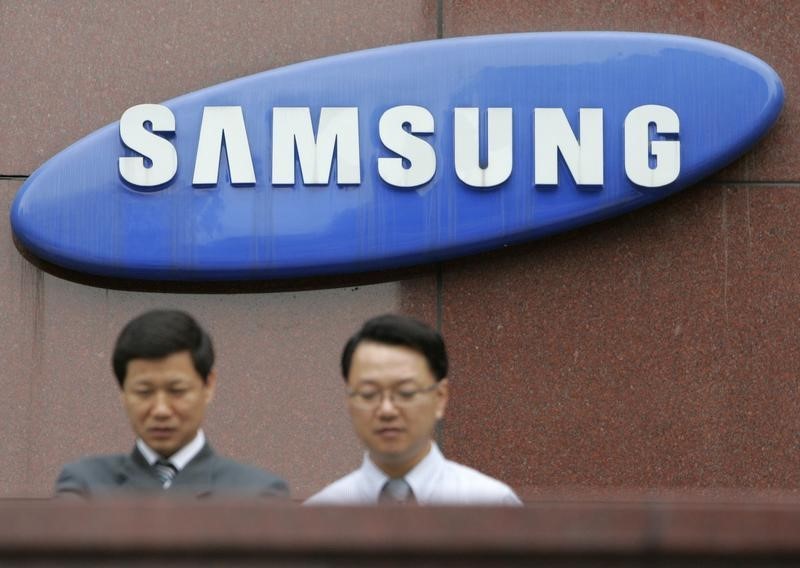 © Reuters. Employees of Samsung Group walk in front of the company's logo at its headquarters in Seoul