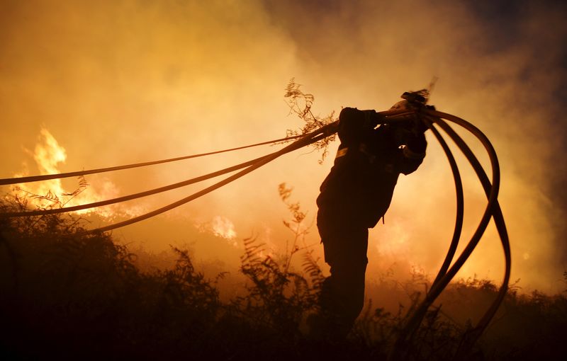 © Reuters. Um bombeiro segura mangueiras enquanto combate um incêndio florestal perto da cidade de Berango, perto de Bilbao, no Norte da Espanha