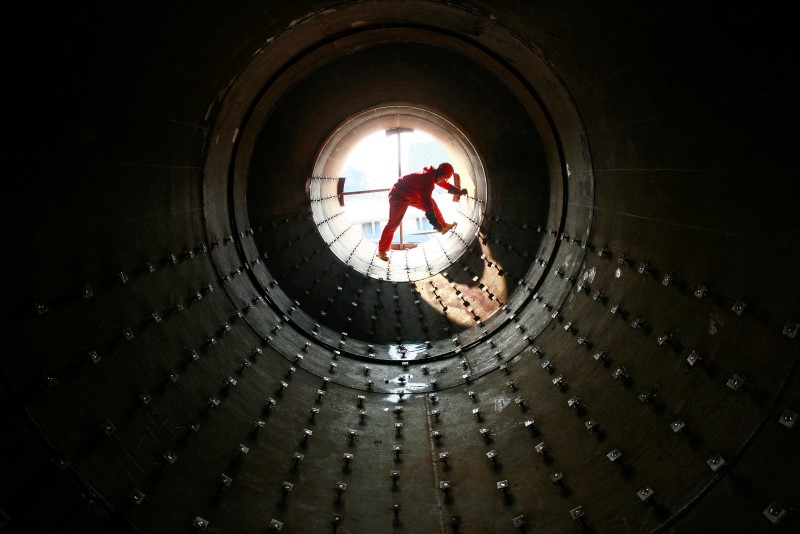 © Reuters. A worker checks steel pipes at an oil field preparing for oil and gas exploitation in Yilong