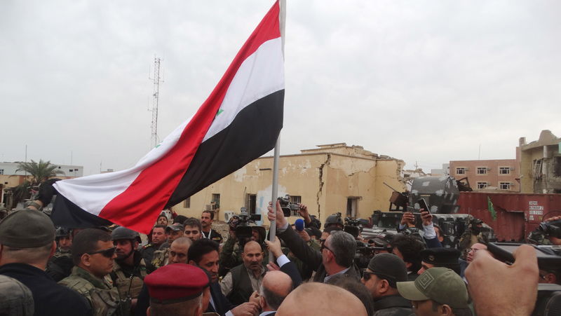 © Reuters. Premiê iraquiano Haider al-Abadi segura bandeira do Iraque na cidade de Ramadi