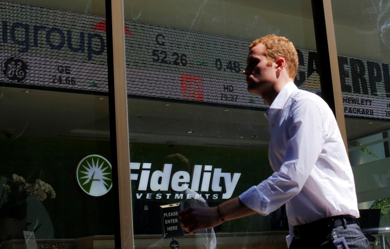 © Reuters. A pedestrian walks past a stock ticker at a Fidelity Investments office in Boston