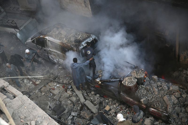 © Reuters. Men put off a fire in a site damaged from what activists said was shelling by forces loyal to Assad in the town of Douma