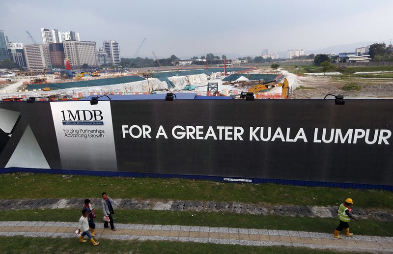 © Reuters. File photo of men walking past a 1 Malaysia Development Berhad (1MDB) billboard at the funds flagship Tun Razak Exchange development in Kuala Lumpur, Malaysia