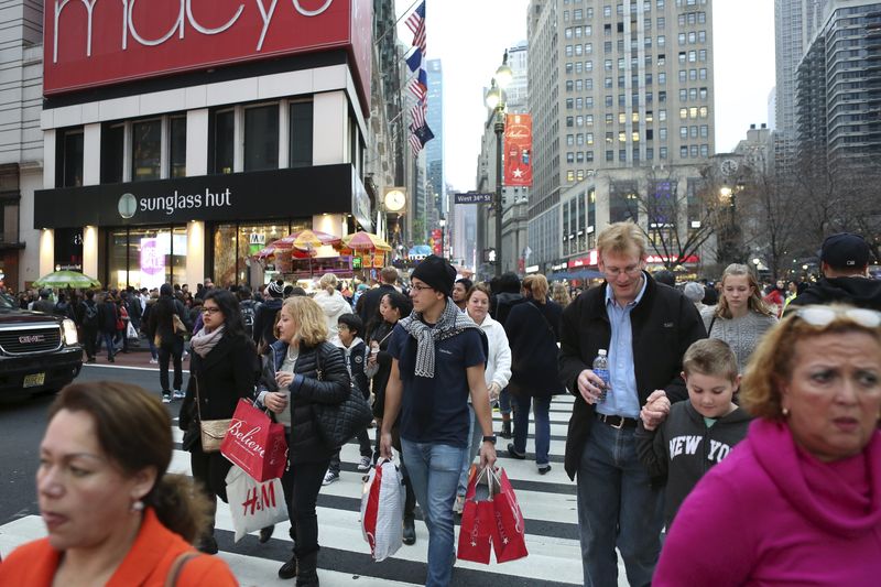 © Reuters. A man in short sleeves carries shopping bags near Herald Square during unseasonably warm weather in Manhattan 