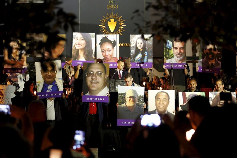 © Reuters. Posters of the 14 people killed are displayed on stage during a vigil for San Bernardino County employees after last week's shooting in San Bernardino, California