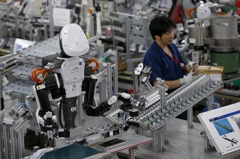 © Reuters. A humanoid robot works side by side with employees in the assembly line at a factory of Glory Ltd., a manufacturer of automatic change dispensers, in Kazo, north of Tokyo