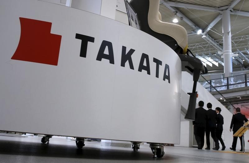 © Reuters. Visitors walk behind a logo of Takata Corp on its display at a showroom for vehicles in Tokyo