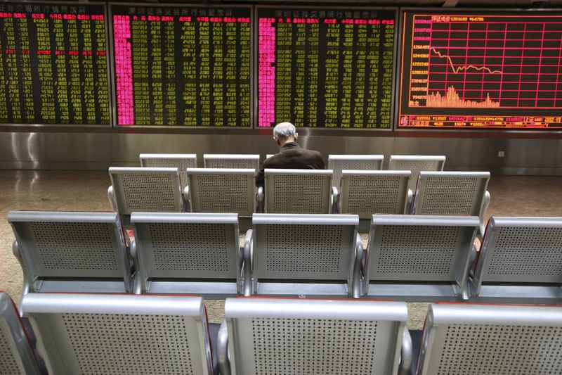 © Reuters. An investor sits in front of an electronic board showing stock information at a brokerage house in Beijing
