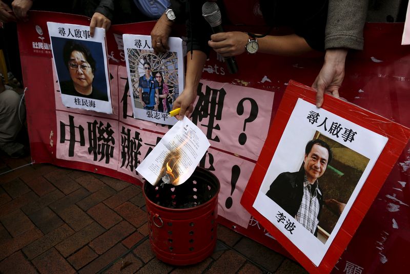 © Reuters. A pro-democracy demonstrator burns a letter next to pictures of missing staff members of a publishing house and a bookstore during a protest to call for an investigation behind their disappearance, outside the Chinese liaison office in Hong Kong