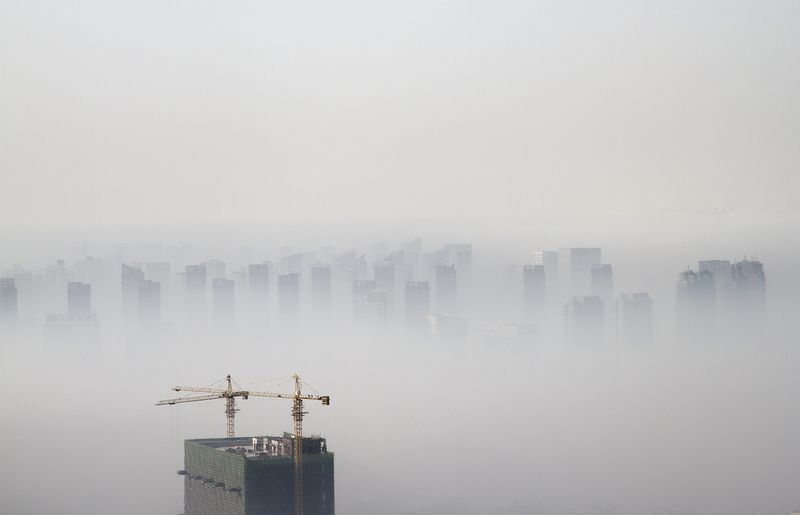 © Reuters. File photo of a building under construction amidst smog on a polluted day in Shenyang