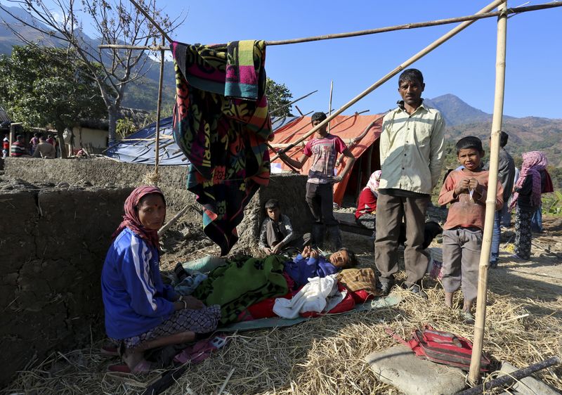 © Reuters. People look on as they stay outdoors after an earthquake at P.Molding village on the outskirts of Imphal