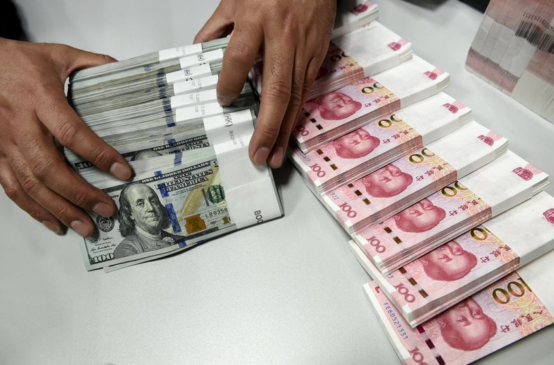 © Reuters. Funcionário movimenta notas de dólar e de iuan em agência do Banco da China em Taiyuan