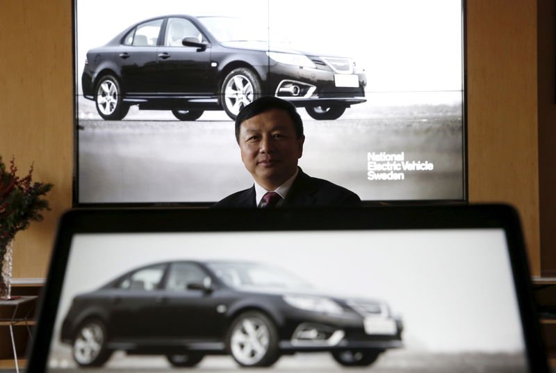 © Reuters. National Electric Vehicle Sweden (NEVS) chairman Jiang poses with images of NEVS's electric car on screens at its Beijing headquarters building